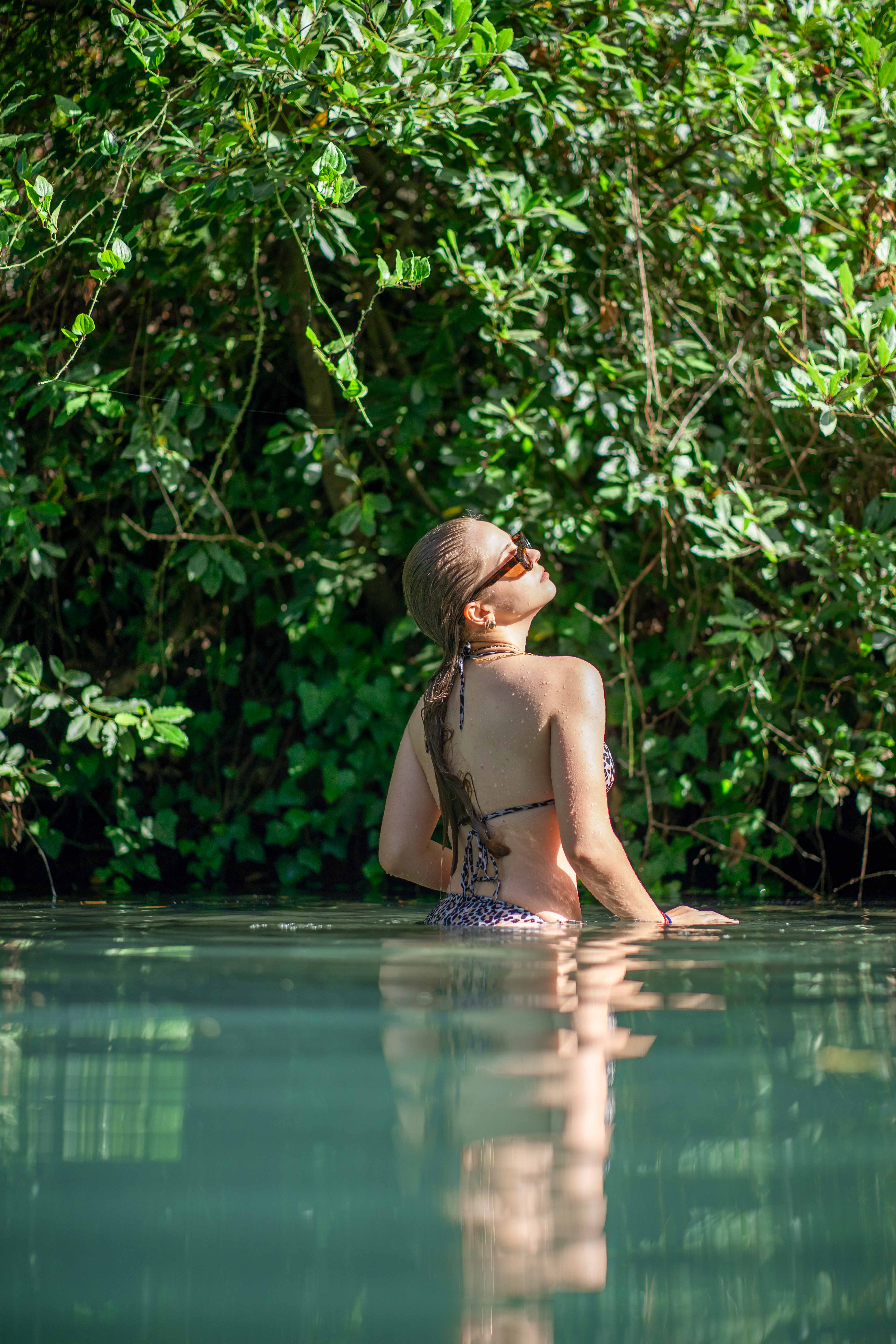 Woman standing in water surrounded by greenery